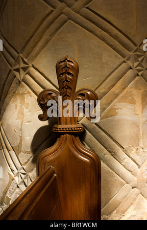 Carved Oak Fleur de Lis on pew end in front of carved stone column in St Peter & Paul's church, Belton, Grantham, Lincolnshire Stock Photo