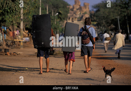 Three climbers walking down the street with crash pads in Hampi, India. Stock Photo