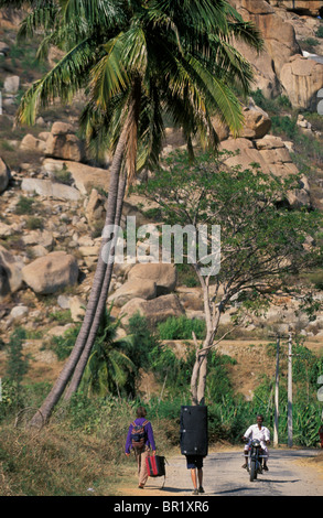 Two climbers walking down a road with their crash pads in Hampi, India. Stock Photo