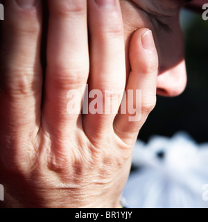 A womans hands against the side of her face. Stock Photo