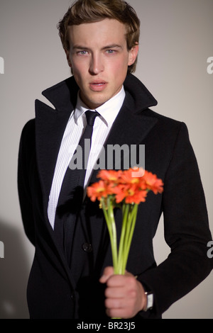 A male model holding flowers during a photo shoot at a studio in Los Angeles, USA. Stock Photo