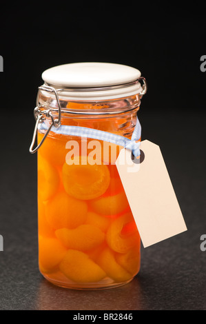 Bottled apricot halves in glass preserve jar with label Stock Photo