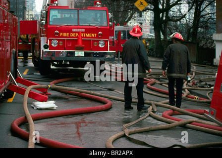 Firefighters / Firemen standing amidst Fire Hoses and Truck, Vancouver, British Columbia, Canada Stock Photo