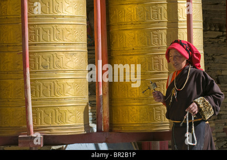 Tibetan Buddhist pilgrims turn golden prayer wheels at Huiyuan Temple, Bamei, Sichuan Province, China Stock Photo