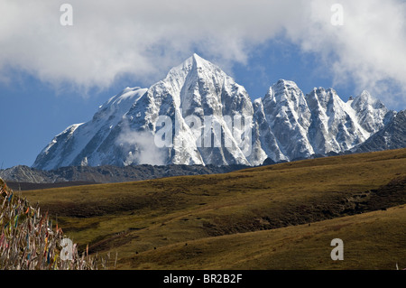 Yala Mountain's snow covered peak rises above hillside prayer flags, Bamei, Sichuan Province, China Stock Photo