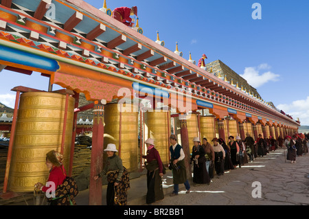 Tibetan Buddhist pilgrims turn golden prayer wheels at Huiyuan Temple, Bamei, Sichuan Province, China Stock Photo