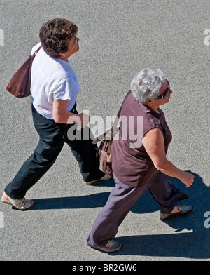 Two mature / middle-aged women walking along pavement - France. Stock Photo