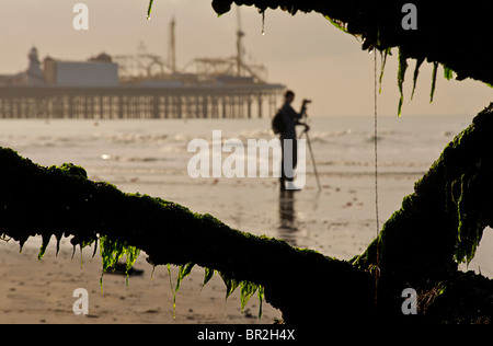 Silhouette of the Palace Pier now called Brighton Pier and photographer, Brighton. Low tide. East Sussex, England Stock Photo