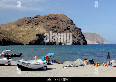 Landscape view of beach at las Negras with fishing boats on sandy shore and black rocky headland in distance Stock Photo