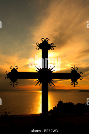 Iron cross with monastery in the bottom right in the sunset on Mount Athos, Greece Stock Photo