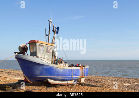 Traditional small fishing boat that has been pulled up onto the beach at Hythe, near Folkestone, Kent, UK. Stock Photo