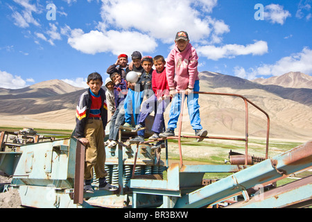 Children playing on rusted old equipment in Bulunkul in the Pamirs, Tajikistan Stock Photo