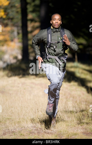 African American man, Cupid Alexander, runs through grass on forest trail near Mt. Hood in the Cascade Mountains, Oregon. Stock Photo