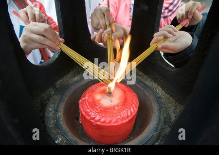 Teen girls light incense bundles while visiting, Wenshu Temple, Chengdu, Sichuan Province, China Stock Photo
