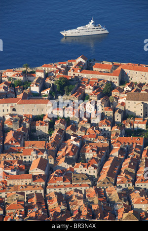 DUBROVNIK, CROATIA. A luxury yacht sailing past the walled old town at dawn. 2010. Stock Photo