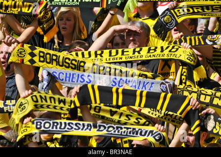 Fans of german football club Borussia Dortmund display scarves with their team colors. The blue scarf insults rival club Schalke Stock Photo