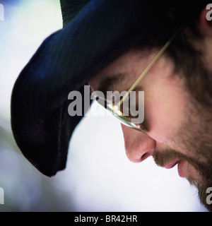 Profile of a bearded young man wearing a black hat and sunglasses. Stock Photo