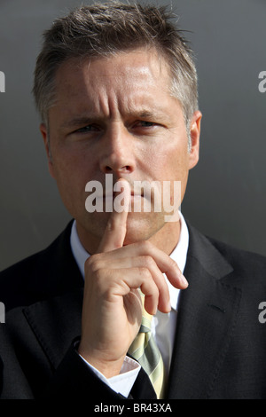 Businessman putting his finger on the mouth, portrait Stock Photo