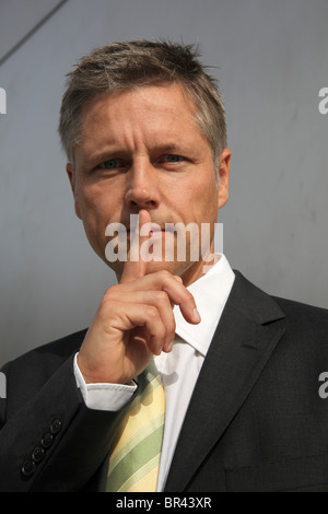 Businessman putting his finger on the mouth, portrait Stock Photo