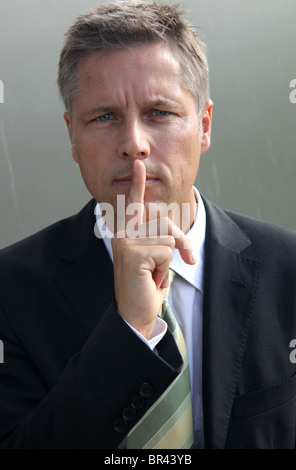 Businessman putting his finger on the mouth, portrait Stock Photo