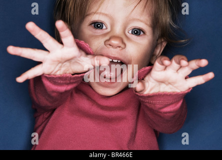 A one year old girl laughs and giggles while reaching towards the camera in Flagstaff, Arizona. Stock Photo