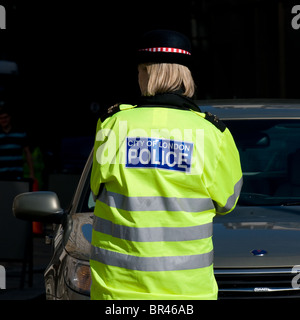 Rear view of a City of London female police officer on duty in London in the UK. Stock Photo