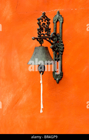 Old vintage bell on a orange wall Stock Photo