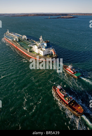Oil tanker being piloted by tug boats into Portland Harbor Maine. Stock Photo