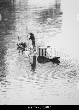 Fisherman casting fishing net on bamboo raft on Li River, Yangshuo, Guangxi, China Stock Photo