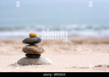A pile of round smooth zen rocks stacked in the sand at the beach. Stock Photo