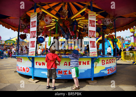Two young boys having a go on the colourful Hook a Duck fairground stall at Barry Island Stock Photo