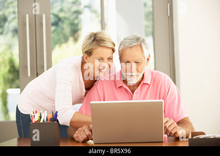 Adult Daughter And Senior Father Using Laptop At Home Stock Photo