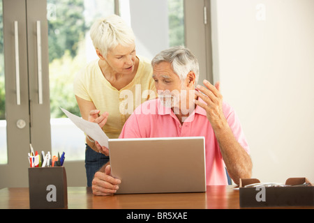 Worried Senior Couple Using Laptop At Home Stock Photo