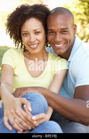 Portrait Of Young Couple Sitting In Park Stock Photo