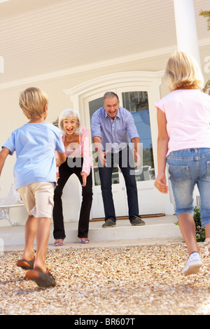 Grandparents Welcoming Grandchildren On Visit To Home Stock Photo
