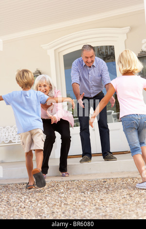 Grandparents Welcoming Grandchildren On Visit To Home Stock Photo