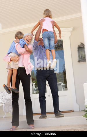 Grandparents Welcoming Grandchildren On Visit To Home Stock Photo