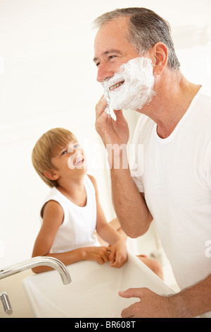 Grandson Watching Grandfather Shaving In Bathroom Mirror Stock Photo