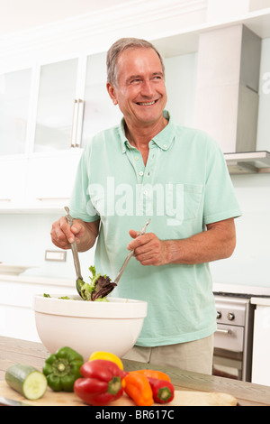 Senior Man Preparing Salad In Modern Kitchen Stock Photo