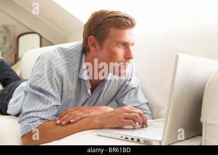 Man Using Laptop Relaxing Sitting On Sofa At Home Stock Photo