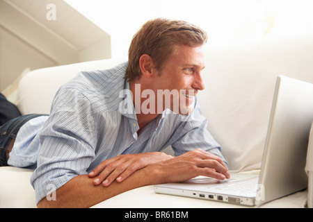 Man Using Laptop Relaxing Sitting On Sofa At Home Stock Photo