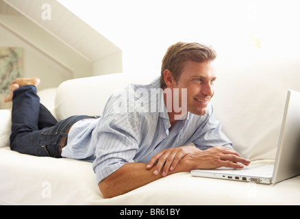 Man Using Laptop Relaxing Sitting On Sofa At Home Stock Photo