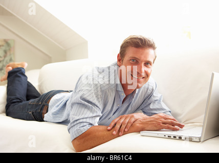 Man Using Laptop Relaxing Sitting On Sofa At Home Stock Photo