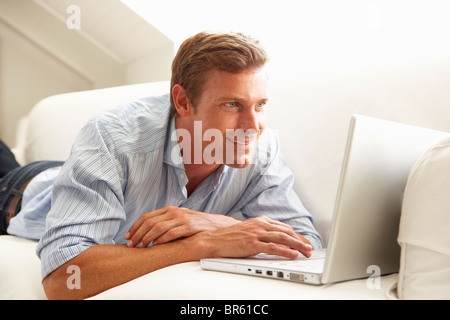 Man Using Laptop Relaxing Sitting On Sofa At Home Stock Photo