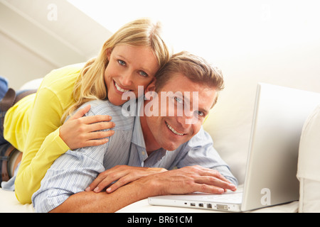 Couple Using Laptop Relaxing Sitting On Sofa At Home Stock Photo