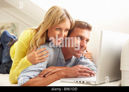 Couple Using Laptop Relaxing Sitting On Sofa At Home Stock Photo