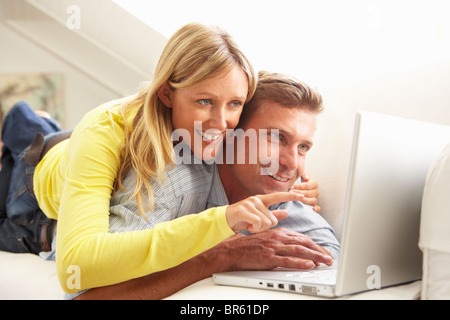 Couple Using Laptop Relaxing Sitting On Sofa At Home Stock Photo