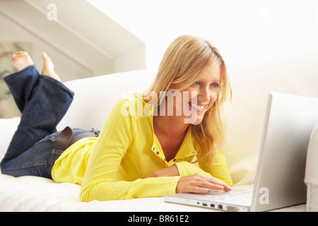 Woman Using Laptop Relaxing Sitting On Sofa At Home Stock Photo