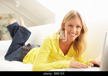 Woman Using Laptop Relaxing Sitting On Sofa At Home Stock Photo