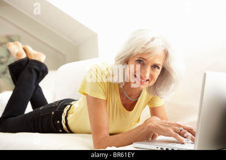 Senior Woman Using Laptop Relaxing Sitting On Sofa At Home Stock Photo